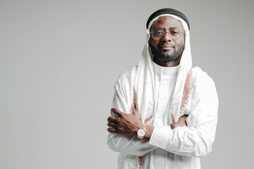 Smiling arabic man in special clothes looking at the camera with his arms crossed over his chest