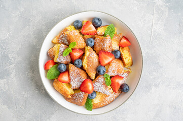 Kaiserschmarrn - traditional austrian pancake dessert with fresh berries and powdered sugar on a gray concrete background. Sweet breakfast. Copy space.