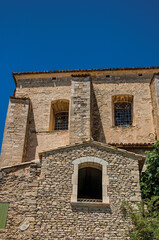 Facade of stone house looking like a face, in an alley of the historical city center of Gordes. Provence region, southeastern France.