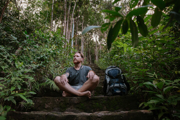 Male tourist climbs up the mountain in the tropical forest.