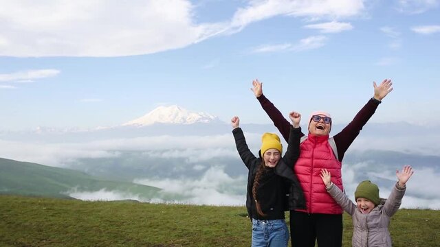 happy grandmother and grandchildren shout hurrah at top of mountain. active recreation for children and elderly. tourism, travel.