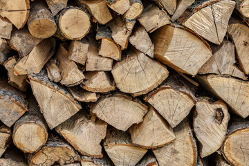 Background of hewed smooth wooden logs. Cut wood texture. Pile of chopped fire wood prepared for winter