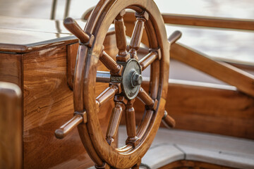 A close-up of instruments and wooden wheel of nautical vessel. Sailboat at sea background © Jevgenija Zukova