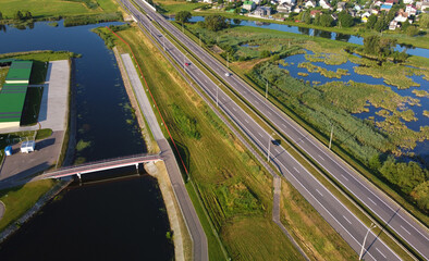 Aerial view of highway road and green meadows and fields