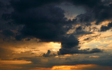 Fototapeta premium beautiful sunset sky, bright sun and dark silhouette of clouds as a background
