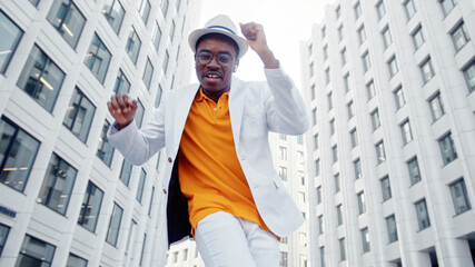 Professional freestyle dancer in suit and glasses dances on street among large city office buildings