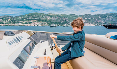 Captain boy drives the yacht. Travel adventure concept. Yachting with child on summer vacation....
