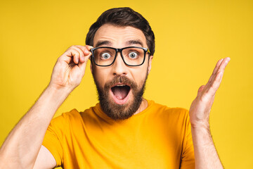 Happy winner! Portrait of shocked amazed young male man keeps mouth widely opened, being surprised, expresses great surprisment. Isolated over pink yellow background.