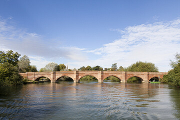 Fototapeta na wymiar The brick bridge built by Sir Gilbert Scott in 1864 over the River Thames at Clifton Hampden, Oxfordshire, UK