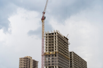 Fototapeta na wymiar Monolithic concrete frame of apartment building under construction with partially attached ready-made facade cladding blocks
