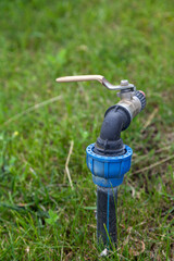 Water irrigation tap in middle of grass lawn close-up