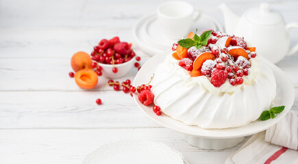 Homemade Pavlova cake with fresh raspberries, red currants and apricots. Copy space.  Selective focus 