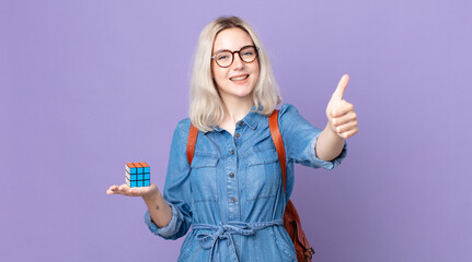 young pretty albino woman feeling proud,smiling positively with thumbs up and solving an...