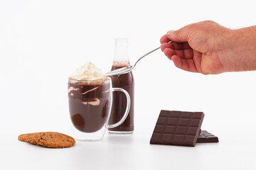 Male hand with spoon over cup of chocolate milkshake and whipped cream: Chocolate concept.