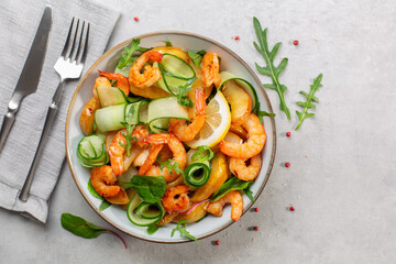 Fresh salad with grilled prawns, caramelized pears, cucumber and mixed greens, with lemon dressing.  Light grey background. Directly above. Copy space.