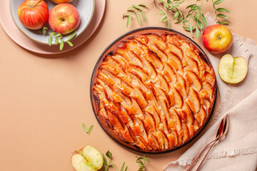 Apple pie decorated with apple slices and glazed. Fresh apple fruits, on a peach background. Copy space. - obrazy, fototapety, plakaty