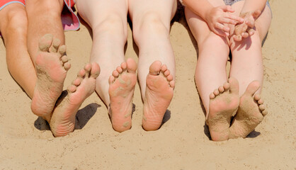 Feet of a family relaxing on a sandy beach