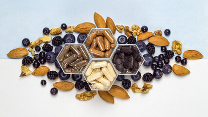 Various capsules with dietary supplements or vitamines, fresh blueberry and nuts