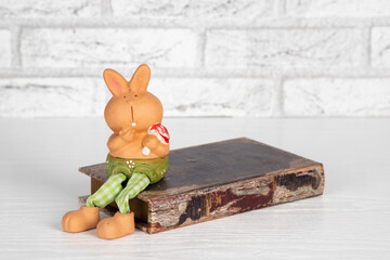 Decorative ceramic toy rabbit sits on an old book