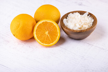 close up of three oranges and a bowl of coconut flakes as ingredients