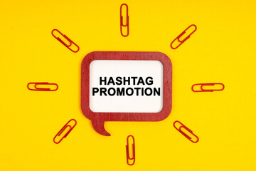 On a yellow background, paper clips and a mental plaque with the inscription - Hashtag Promotion