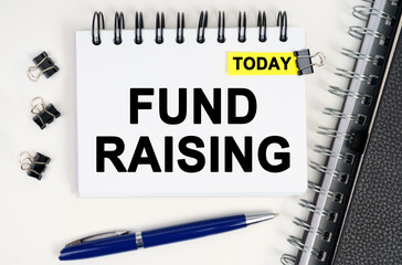 On the table is a pen and a notebook with inscriptions - Today and FUND RAISING