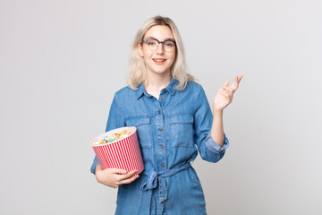 young pretty albino woman feeling happy, surprised realizing a solution or idea with a pop corns...