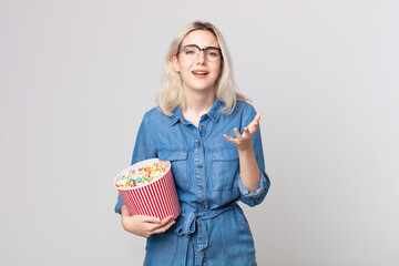 young pretty albino woman looking desperate, frustrated and stressed with a pop corns bucket