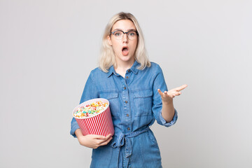 young pretty albino woman feeling extremely shocked and surprised with a pop corns bucket