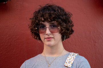 Retrato de joven con el pelo rizado y gafas de sol grandes en distintas aptitudes.