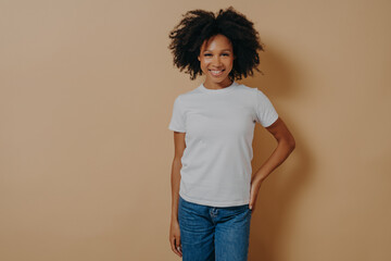 Cheerful african female in white tshirt and jeans expressing positive emotions, posing in studio