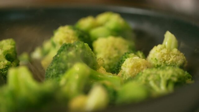 Skillet full of freshly cut broccoli cooking on the stove top - slow motion
