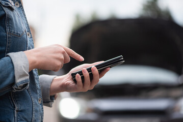 Woman with mobile phone on the broken car background. Tow truck service. Car service call.