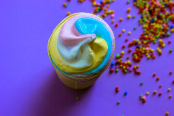 Colorful cool ice-cream in a waffle cup on a multicolored beads creative background flatly. A trendy colors of summer 2021 - pastel blue, pink, yellow. High-calorie sweet snack. Summer food concept.