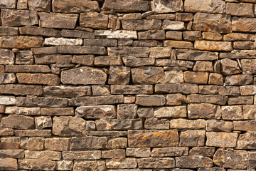 Rustic stone wall texture. Irregular stone wall in natural colors, brown, ocher. Textured background