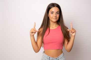Young girl in summer clothes pointing fingers up isolated over white background.