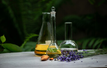 Set of the bottles and flasks with essence fragrance cosmetic herbal mint and lavender oils with almonds on desk. Spa and wellness setting, relax and treatment therapy. Selective focus