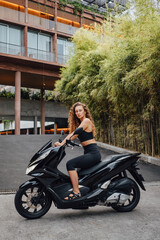 Plakat Sportswoman riding modern bike against luxurious mansion