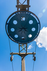 Fragment of the ski lift. Elements of the steel structure, wheel, steel ropes, tensions, sensors, electric wires on the background of the blue sky.
