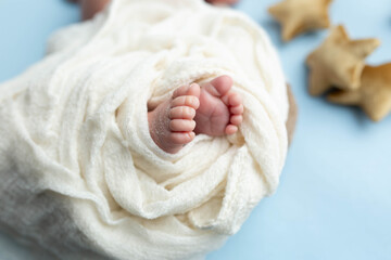 a small leg of the newborn in a white scarf. soft focus