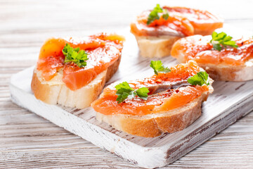 Slice of bread with smoked salmon and butter on wooden background. Grain yeast-free bread butter, parsley and fish on a wooden board.