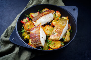 Modern style traditional fried skrei cod fish filet with fried potato, fruits and olives served as...