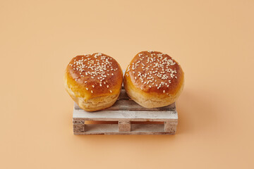 Wooden pallets with burger buns on orange pastel background