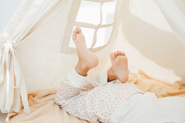 Child girl feet in teepee. Playing at home