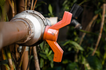 Orange water tap with a black faucet blurred in the background. Mention to gardening and food...