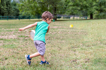 Fototapeta premium smiling cute child playing with an old tennis racket in a public park
