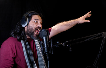 Fototapeta na wymiar View of a Hispanic man with beard wearing a scarf and a headset recording podcast in the studio