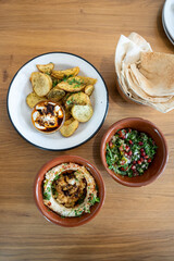 Top down view of a meze table with za'atar fries, hummus, tabbouleh and Lebanese bread, no people