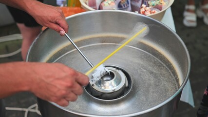 The process of making cotton candy on the street.