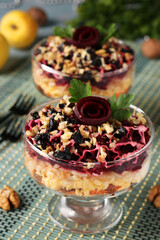 Traditional Russian salad with cheese, beets and carrots, decorated with beet roses, nuts and prunes, portioned serving.